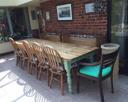 long farmhouse table with green legs and antique chairs
